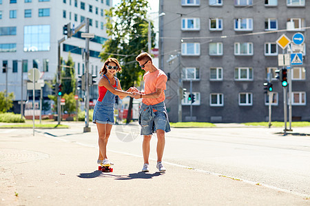 暑假,极限运动人们的快乐的十几岁的夫妇骑着短的现代巡洋舰滑板城市街道图片