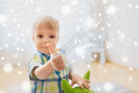童,玩具人的快乐的小男孩玩骑玩具马,并家里雪上竖大拇指图片