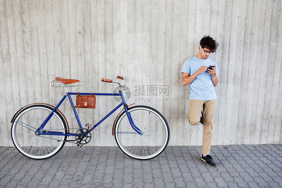 人,通信,技术,休闲生活方式时髦的男人,智能手机耳机固定齿轮自行车上听音乐城市街道图片