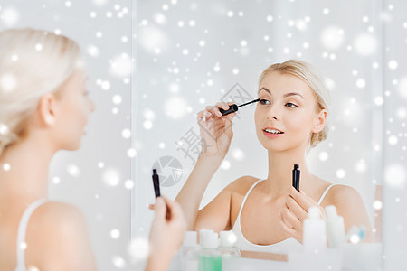 美丽,化妆,化妆品,早晨人的微笑的轻女人用睫毛膏化妆,家里的浴室雪地上照镜子图片