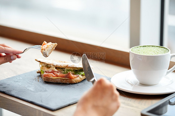 食物,晚餐人们的女人吃鲑鱼帕尼尼三明治与杯抹茶绿茶铁餐厅图片