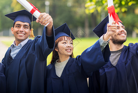 教育毕业人的群快乐的国际学生穿着灰浆板学士服,毕业证书庆祝成功文凭的迫击炮板上快乐的学生图片