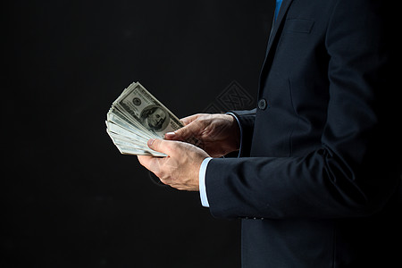 人,商业,财务货币商人的手持美元现金黑色背景密切商人的手着钱图片