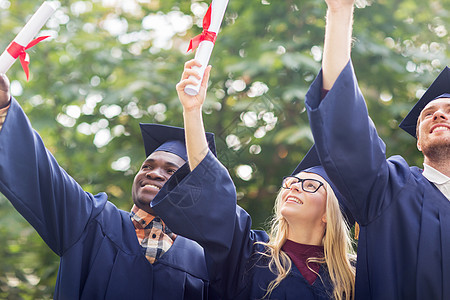 教育毕业人的群快乐的国际学生穿着灰浆板学士服,毕业证书庆祝成功文凭的迫击炮板上快乐的学生图片