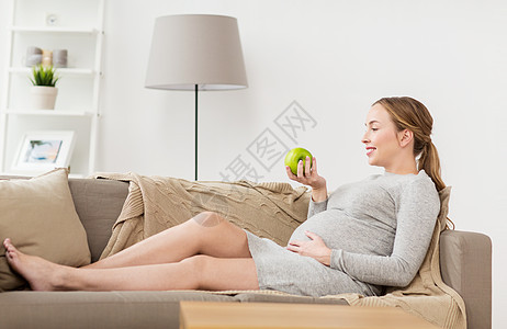 怀孕,健康,食物人的快乐的孕妇坐沙发上,着绿色的苹果带着绿苹果的快乐孕妇图片