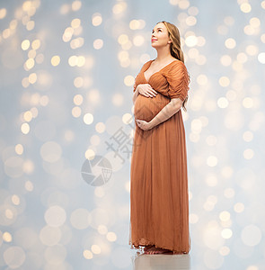怀孕,母亲,人期望的快乐的孕妇触摸她的大腹便便的节日灯光背景快乐的孕妇抚摸她的大肚子图片