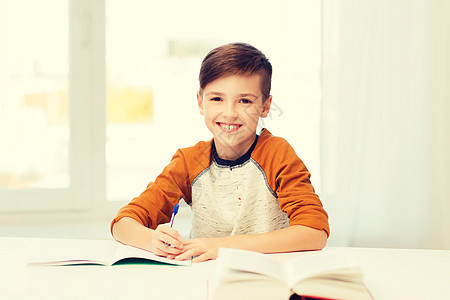 教育,童,人,家庭作业学校的微笑的学生男孩带着书家里写笔记本微笑的学生男孩家里写笔记本图片