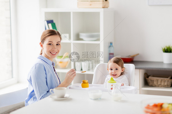 家庭,食物,饮食,早餐人们的快乐的母亲与纯净物勺子喂养小婴儿坐家里的高椅子上快乐的母亲家里给婴儿喂养婴儿图片