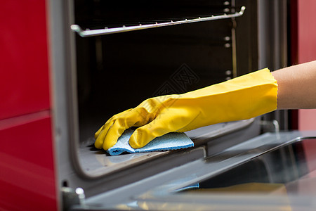 烤箱手套人,家务家务手橡胶手套与抹布清洁烤箱家里厨房家庭厨房用抹布清洁烤箱背景