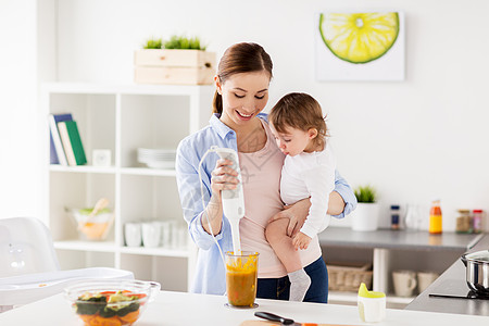家庭,食物,健康的饮食,烹饪人们的快乐的母亲与搅拌机混合蔬菜泥小女婴与家厨房快乐的母亲婴儿家厨房饭图片