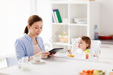家庭,食物,饮食,早餐人们的快乐的母亲与平板电脑小婴儿坐高椅子家里厨房快乐的母亲婴儿家里吃早餐图片