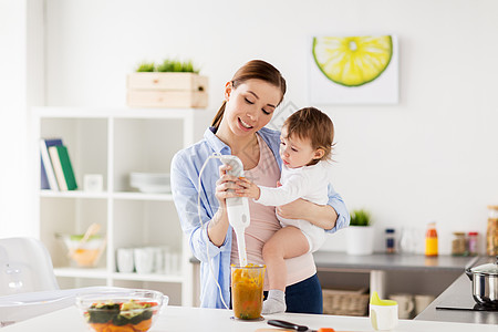 家庭,食物,健康的饮食,烹饪人们的快乐的母亲与搅拌机混合蔬菜泥小女婴与家厨房快乐的母亲婴儿家厨房饭图片