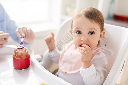 家庭,食物,饮食人的母亲与纯净物勺子喂养小婴儿坐高椅子家里母亲家用泥喂婴儿图片