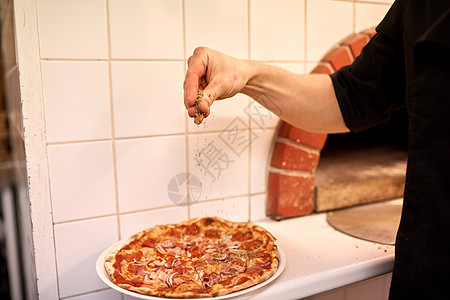 食物,烹饪,意大利菜,人烹饪烹饪手添加胡椒意大利腊肠比萨饼比萨饼店披萨店给意大利腊肠披萨里加胡椒图片