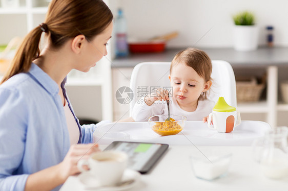 家庭,食物,早餐人们的快乐的母亲与平板电脑小婴儿坐高椅子上,吃纯净物家里的厨房快乐的母亲婴儿家里吃早餐图片