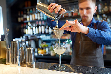 酒精饮料,人奢侈的酒保把鸡尾酒床过滤器倒入酒吧的璃调酒师酒吧准备鸡尾酒图片