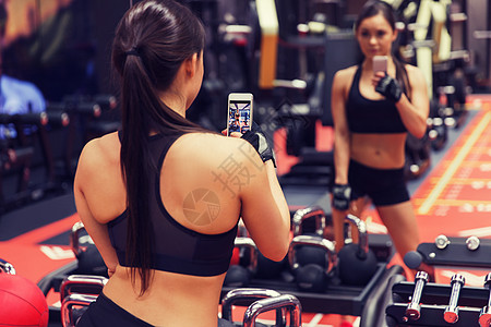 运动,健身,生活方式,技术人的轻的女人带着智能手机健身房自拍智能手机的女人健身房里自拍图片