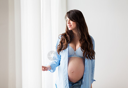 怀孕,母亲,人期望的快乐的孕妇,大肚腩透过窗户看家快乐的孕妇家里大肚子图片