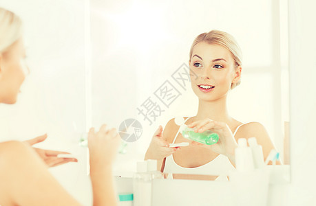 美丽,皮肤护理人的微笑的轻妇女应用乳液棉花盘,以洗她的脸浴室轻的女人浴室洗洗脸图片