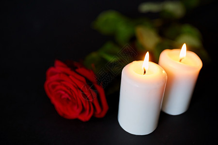 黑色背景下红色玫瑰和燃烧的蜡烛图片