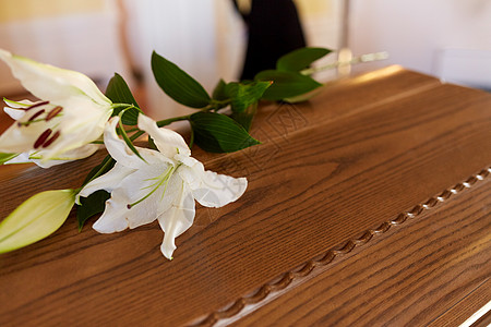 葬礼哀悼白色百合花木制棺材盖葬礼教堂教堂葬礼上木棺上的百合花背景图片