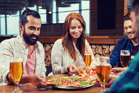 休闲,食物饮料,人假日的微笑的朋友餐馆酒吧吃比萨饼喝啤酒朋友们餐厅用啤酒吃比萨饼图片