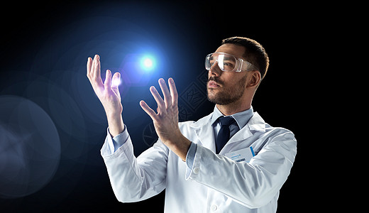 科学,未来技术人的男医生科学家穿着白色实验室外套安全眼镜,背景为黑色科学家穿着实验室外套带光的护目镜背景图片