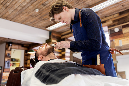 美容人的男人理发师与修剪剃须刀切割胡须理发店男人理发师沙龙剪胡子图片