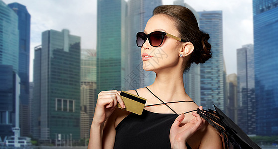 销售,财务,人豪华快乐美丽的轻女人戴着黑色太阳镜,信用卡购物袋新加坡城市摩天大楼的背景带着信用卡购物袋的快乐图片