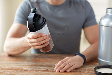 运动,健康的生活方式人们的接近男人穿着健身追踪器与罐子瓶子准备蛋白质奶昔用蛋白瓶罐子把人关来背景图片