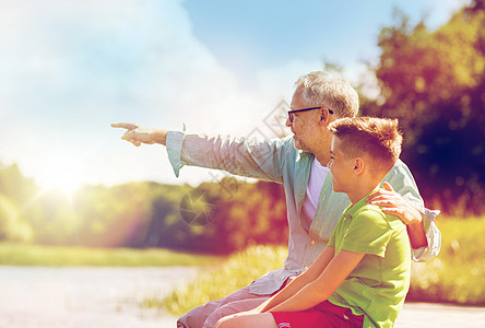 家庭世代交流人的快乐的祖父孙子坐河边祖父孙子坐河泊上图片