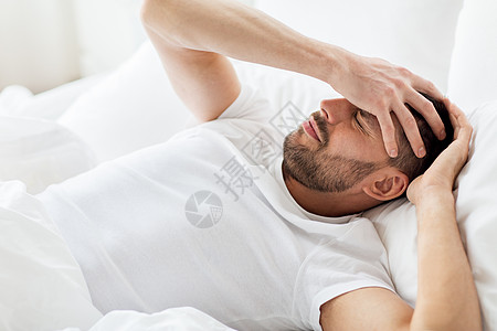 床上男人人,睡觉时间休息的男人躺床上,患头痛宿醉家卧床的人头痛背景