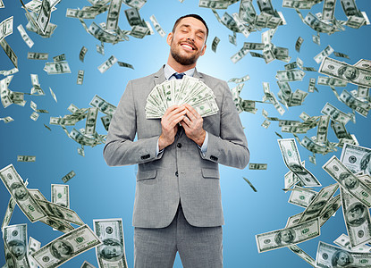 商业,人财务微笑的商人与捆绑的美元现金蓝色背景微笑的商人带着美元的钱图片