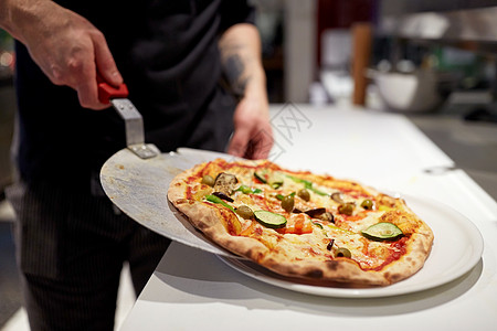食物烹饪,烹饪人的厨师包师把比萨饼果皮盘子比萨饼店披萨店用烤披萨皮饼图片
