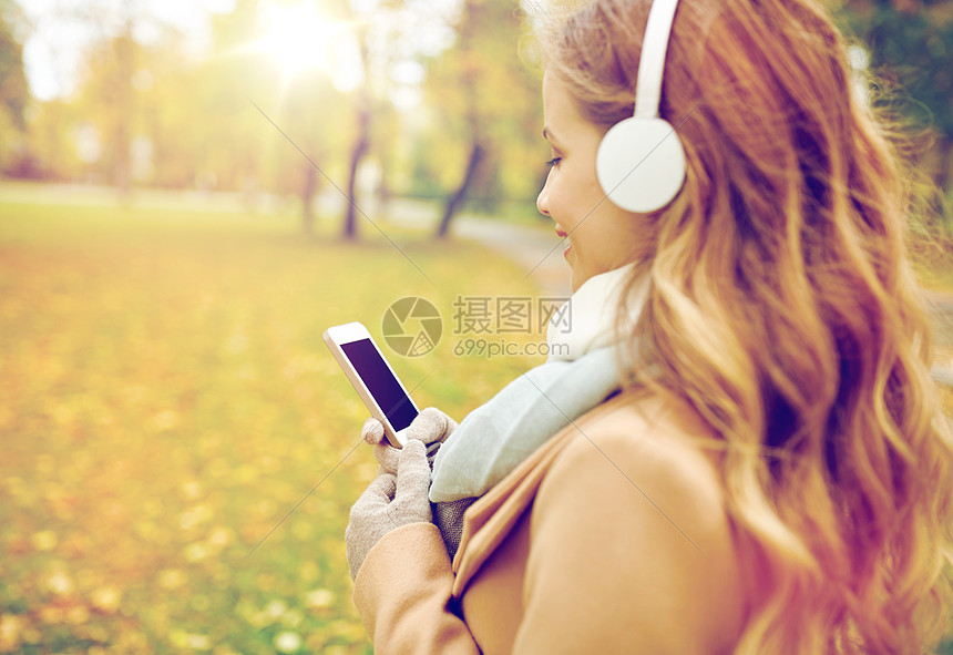 季节技术人的美丽的快乐轻妇女戴着耳机听音乐智能手