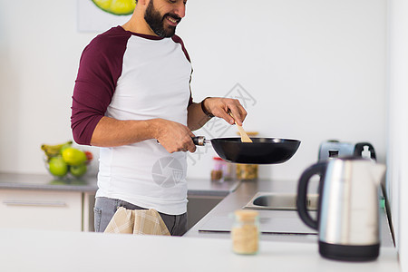 健康的饮食,烹饪人的接近男人与煎锅烹饪食物家里厨房家里厨房里煎锅烹饪食物的男人图片