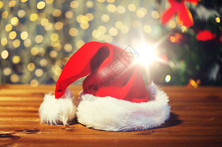节日,诞节,服装传统诞老人帽子木制桌子上的灯光背景把诞老人帽子关灯光下的木桌上图片