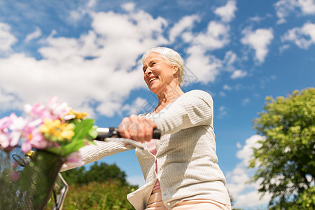 积极的老,人生活方式的快乐的老妇女骑固定自行车夏季公园快乐的高级女人夏季公园骑自行车背景图片