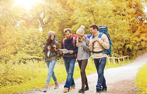 冒险,旅行,旅游,徒步旅行人的群微笑的朋友带着背包秋天的森林里散步群微笑的朋友带着背包徒步旅行图片