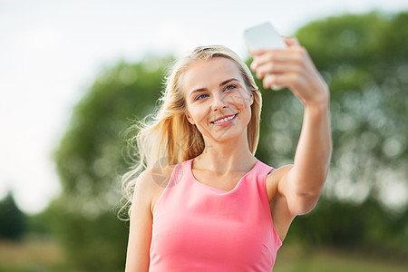 技术人的快乐的轻美女与智能手机户外自拍快乐的女人户外用智能手机自拍图片