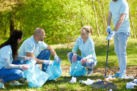 志愿服务慈善人生态理念公园内群带垃圾袋耙清理区域的快乐志愿者志愿者用垃圾袋清洁公园区域图片