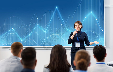 商业,统计人的微笑的女商人讲师与麦克风图表投影屏幕上与学生会议演讲讲座出席商务会议讲座的群人图片