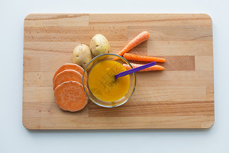 婴儿食品,健康饮食营养蔬菜泥婴儿食品碗与喂养勺子木板上蔬菜泥婴儿食品用勺子放碗里图片