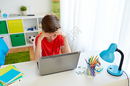 教育,网络欺凌人的悲伤的学生男孩家里的笔记本电脑上遭受欺凌疲惫的学生男孩家着笔记本电脑图片