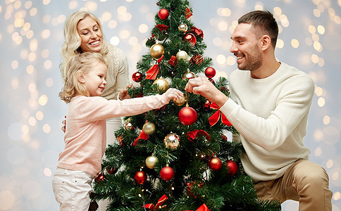 家庭,假期人的快乐的母亲,父亲小女儿装饰诞树的灯光背景幸福的家庭装饰诞树图片