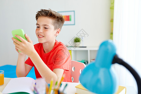 教育,技术沟通快乐的学生男孩分散注意力,家庭作业短信智能手机家里智能手机的学生男孩分散了学的注意力图片