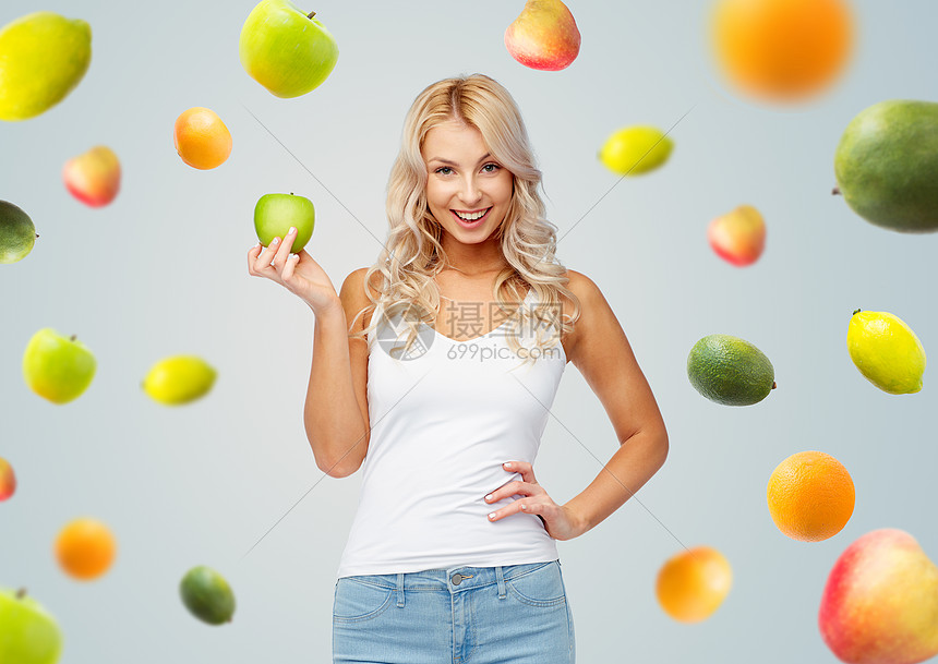 女人与绿色的苹果灰色背景上的水果快乐的美丽的轻女人带着绿色的苹果