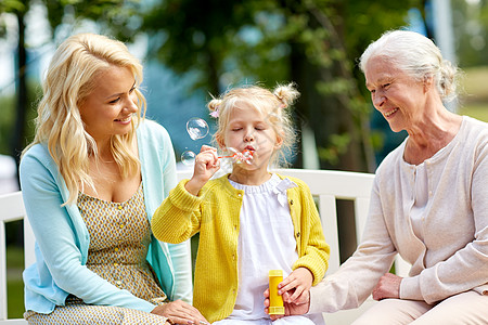 家庭,代人的快乐的微笑的女人与长的母亲小女儿公园肥皂泡快乐的家庭公园肥皂泡图片