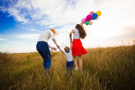 两个女孩个小男孩带着气球田野里跑步妈妈她的孩子家人田野上散步图片