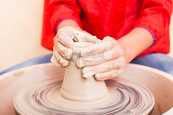女孩的手谁试图用白色粘土陶工的车轮上陶器图片